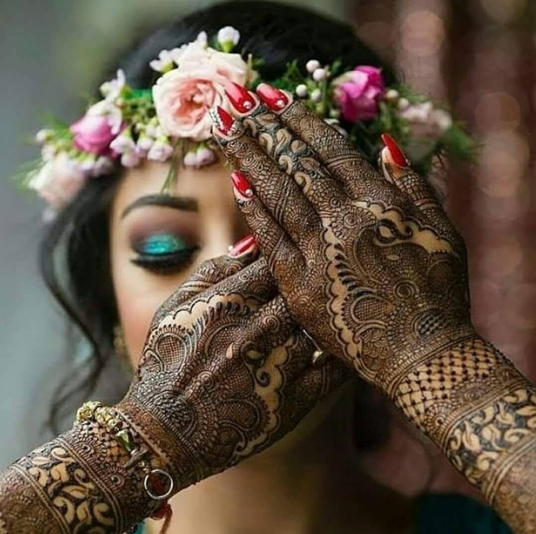 Bride in a fresh flower crown with bridal henna across her hands, styled by Eleglam